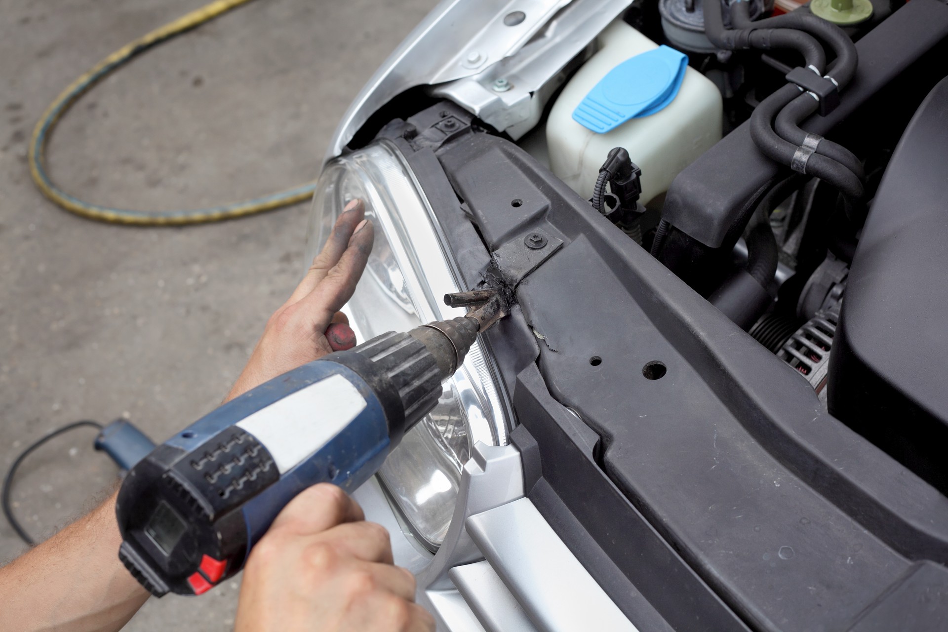 Man drilling the front bumper of a car