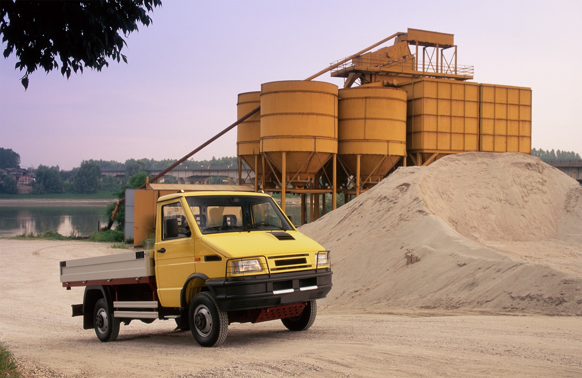 Yellow open box truck in a quarry, near the river
