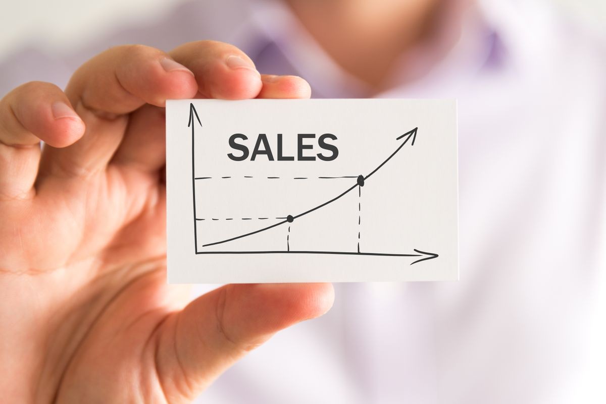 Closeup on businessman holding a card with SALES rising arrow and chart, business concept image with soft focus background